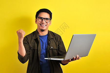 亚洲男人拿着笔记本电脑 手势赢 礼物赢股票游戏商品工具金融在线债券玩家经纪人衍生物图片