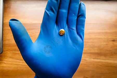 他手里拿着一小块金子 带着手套 金子的迷你宝石奢华橡皮石头掘金矿业树脂电脑蓝色投资矿石图片