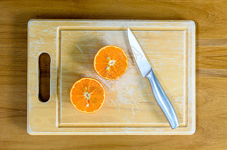 一把刀切橙子热带玻璃果汁茶点木头饮食木块黄色水果白色图片