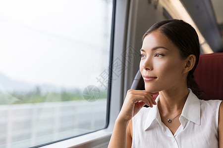 亚洲女性旅行者从火车窗外凝视着户外景色 坐在公共汽车或火车上上班的年轻女士图片