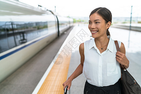快乐的亚洲旅行者微笑着乘坐商务舱的火车旅行 美丽的女人带着手提行李乘坐豪华交通工具离开 早上上班的女商务人士图片
