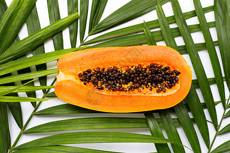 热带棕榈叶上的红木瓜橙子紫色种子甜点营养果汁植物水果树叶食物图片