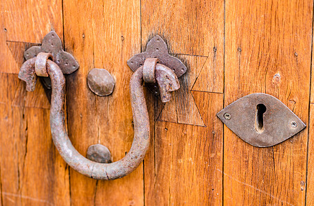 Rusty 门敲锁器和旧木制门的钥匙孔图片