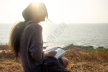 一个亚洲女人 一本有海观的书长发摄影专注地方服装游客天空活动旅行爱好图片