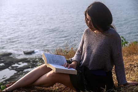 一个亚洲女人 一本有海观的书旅游摄影女性成人活动头发休闲天空棕色专注图片
