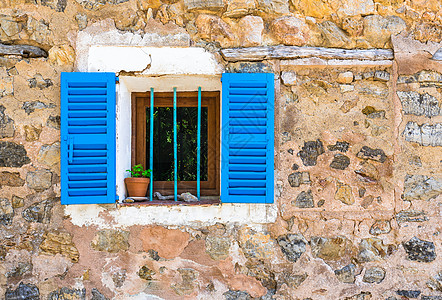 带石墙的地中海房屋的窗户和蓝色百叶窗背景图片