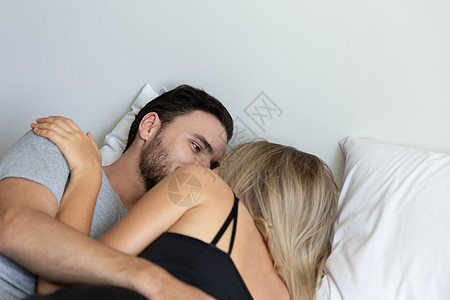 可爱的小情侣拥抱和睡在床上卧室丈夫休息男人金发枕头就寝床单女性女孩图片