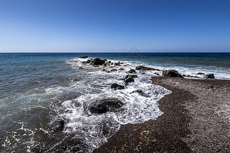 海浪在海滩上冲浪 黑色的挥发沙子和石头热带泡沫海洋支撑海景阳光海岸海岸线液体图片