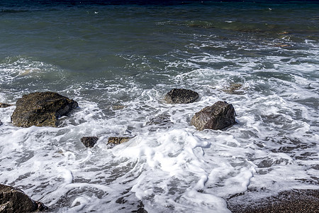 海浪在海滩上冲浪 黑色的挥发沙子和石头液体海岸支撑阳光海洋热带泡沫海岸线图片