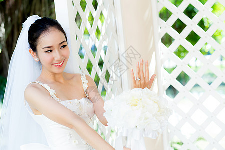 在婚礼当天美丽的年轻女子 穿着白礼服在花园里女性女孩裙子女士庆典花束新娘幸福白色成人图片