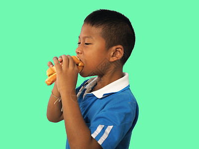 一个男孩吃热狗的肖像 孤立在绿面包上图片