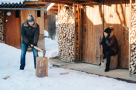 穿着冬衣的家伙 在院子里砍木头夫妻工作喜悦雪堆劈柴惊喜斧头日志村庄木柴图片