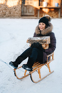 女孩坐在雪橇上 笑着笑着 手里拿着木头图片