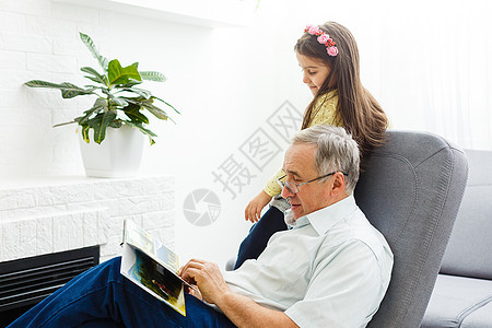 外孙女和祖父在家里的相册上 一起看合影的照片老年孙辈护理享受爷爷女性家庭幸福白发房子图片