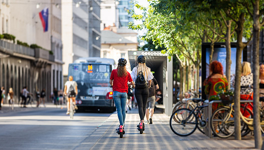 在城市环境中乘坐公共租赁电动滑板车的时尚时尚少女的后视图 斯洛文尼亚卢布尔雅那新型环保现代公共城市交通人行道自行车中心游客街道生图片