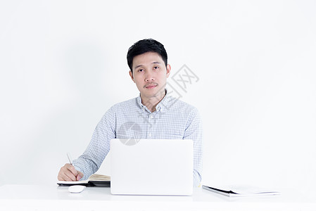 坐在办公桌和与懒惰者一起工作的亚洲雇员工薪男子工人笔记本写作桌子蓝色老鼠人士互联网电脑微笑图片