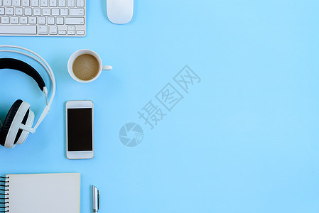 办公室蓝色办公桌和设备 用于与咖啡一起工作的设备笔记本杯子文档老鼠玻璃耳机键盘电话木板高架图片