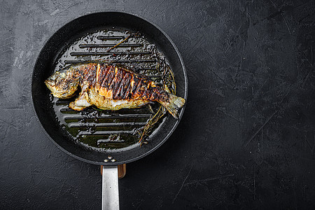 烧烤热锅上的鱼 在纸质黑色底底上方 上面是带文字空间的顶端视图图片