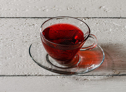 木桌上的卡卡德红茶杯药品草本草本植物叶子盘子红色食物木头桌子花瓣图片
