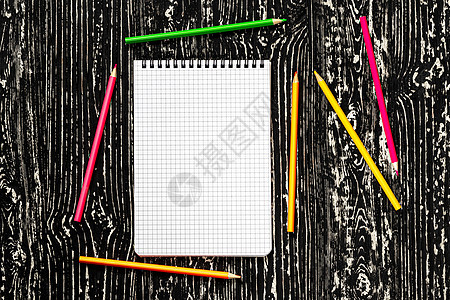 笔记本上有平方页和彩色铅笔 在黑桌上 有复制空间图片