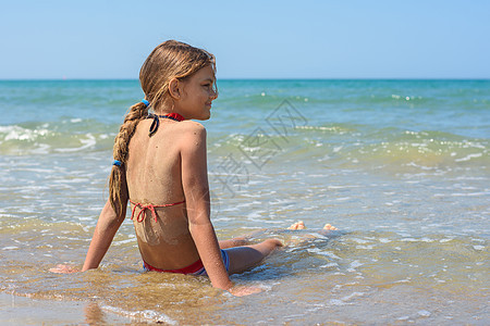 一个十岁的女孩 坐在海边的海水中图片