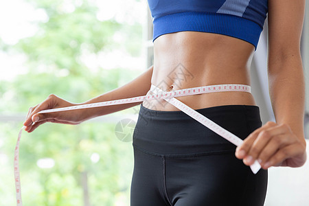 Slim 年轻的年青女性 用测量胶带衡量自己腰部健身房运动磁带女士腹部运动装重量身体福利图片