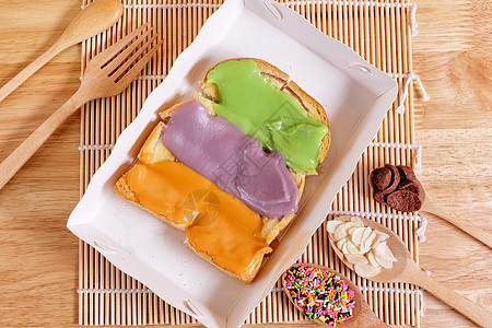 土司吐司 在木本底配有多彩色焦糖酱脆皮木头面包粉色小吃香蕉糕点白色食物黄油图片