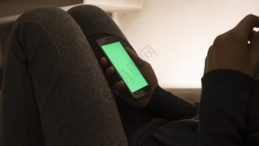 现代夫妻关系和约会概念 女性坐在沙发上的特写镜头 在低光下使用智能手机和空白绿屏互联网屏幕女朋友技术成人黑发女士手指乐趣笔记本图片