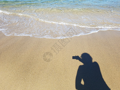 女人用阴影在沙里用水照像相机女孩照片海滩女士女性沿海海洋波浪图片