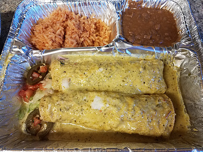 配有绿色酱汁 大米和金属盘中豆子的enchiladas午餐胡椒辣椒托盘图片