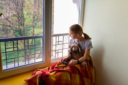 可怜的小女孩坐在窗户上 家里被孤立的玩具 Corona病毒隔离概念风险疾病预防感染保健青少年流感药品卫生女孩图片