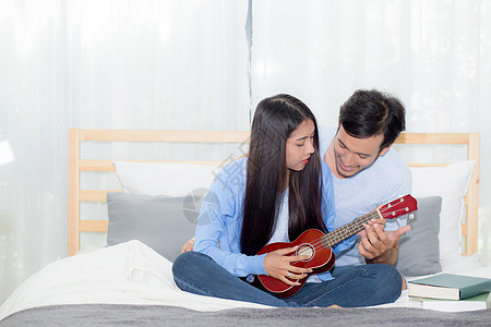 年轻的亚裔夫妇玩着四轮式的游戏卧室女士乐趣乐器浪漫青少年音乐微笑女朋友男人图片