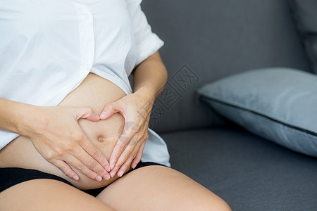 怀着心动象征符号的怀孕女性孕妇肚子形状卫生生育力拥抱压痛胎儿沙发家庭腹部女士婴儿图片