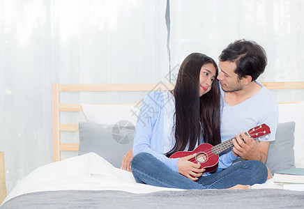 年轻的亚裔夫妇玩着四轮式的游戏长椅房间乐器乐趣浪漫喜悦唱歌男朋友女朋友女士图片