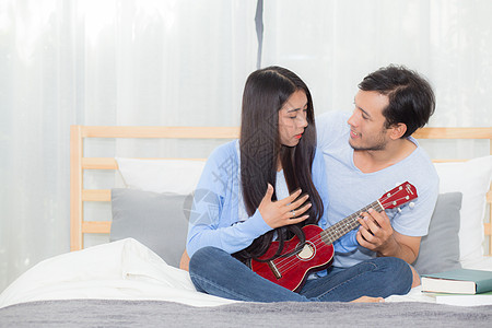 年轻的亚裔夫妇玩着四轮式的游戏微笑青少年喜悦乐趣幸福男朋友房间长椅唱歌男人图片