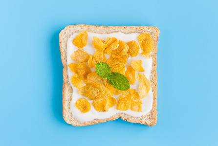 红面包上用薄荷粉在蓝面纸上的酸奶玉米片黄色甜点糕点谷物美食烹饪蓝色薄荷平铺营养图片