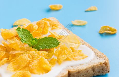红面包上用薄荷粉在蓝面纸上的酸奶玉米片薄荷营养蓝色食物平铺玉米谷物黄色背景美食图片