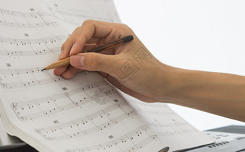 钢琴演奏家的手在钢琴工作人员或木板上写笔记歌曲享受音乐乐谱自然光仪器钢琴谱人手乐器工具图片