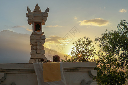 位于印度尼西亚巴厘岛的印度祭坛 剧烈的日落光 背景中美丽的山 在日落期间拍摄的印度祭坛 白石祭坛石头旅游上帝宗教花园艺术天空文化图片