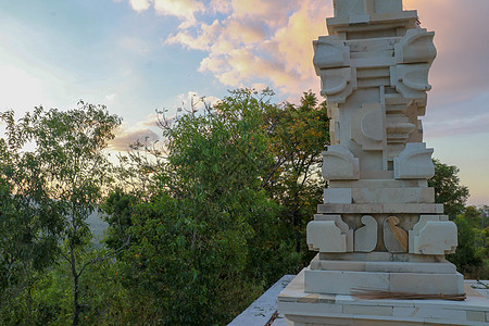 位于印度尼西亚巴厘岛的印度祭坛 剧烈的日落光 背景中美丽的山 在日落期间拍摄的印度祭坛 白石祭坛艺术热带纪念碑情调入口寺庙旅行旅图片