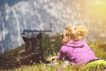 看到背面的女旅行者 和一只狗躺在草地上图片