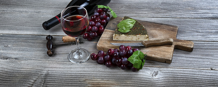 一杯红葡萄酒 配奶酪加面包叶和葡萄图片