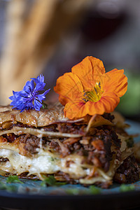 蓝色盘子上的千层面面条美食旱金莲面包乡村木头餐厅橙子脆皮蔬菜午餐图片