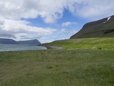 在冰岛西部峡湾自然保护区的 latrar 可以看到 adalvik 湾 那里有生锈的拖拉机和夏季小屋 有绿草草甸 石滩 海洋 积图片