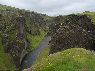 冰岛Eldgja峡谷的悬崖和山丘 花朵与蓝天背景的草地 在冰河流及绿苔上覆盖面貌图片