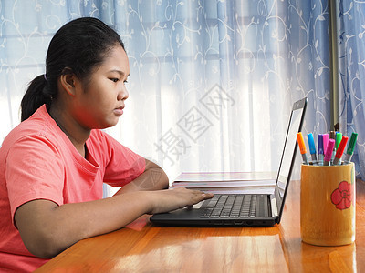一个亚洲女孩正在观看电脑屏幕 以在网络上学习图片
