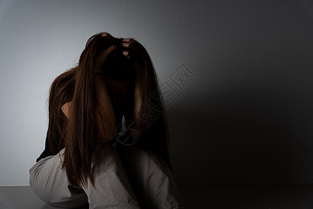 悲伤的女人拥抱她的膝盖 独自坐在黑暗的房间里哭泣 抑郁 不快乐 压力和焦虑症的概念地面疼痛女性女士挫折情感郁闷寂寞悲哀孤独图片