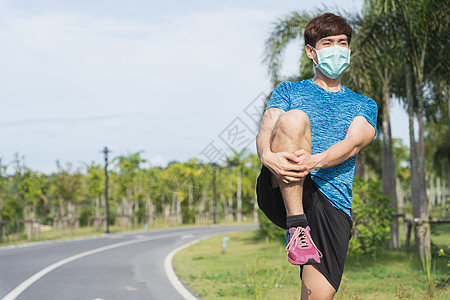 年轻男子戴医疗面具 在W之前伸展双腿疾病卫生日出保健训练慢跑者治疗面具活力封锁图片