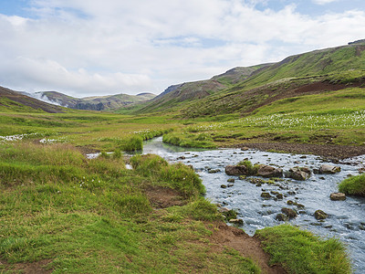 Reykjadalur山谷有温泉河 青草草地和山丘带地热蒸汽 南冰岛靠近Hveragerdi市 阳光明媚的夏日清晨 蓝天踪迹活动图片