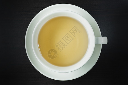 白色杯子茶的顶端景色 黑木地板上的位置图片